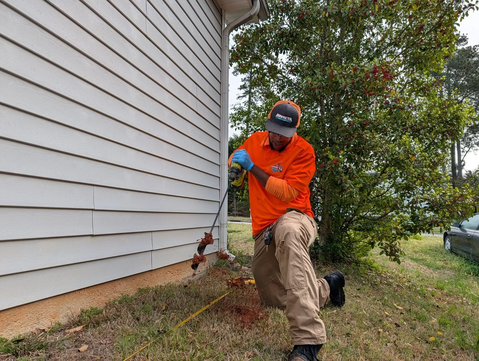 Invicta technician treating along the side of a house