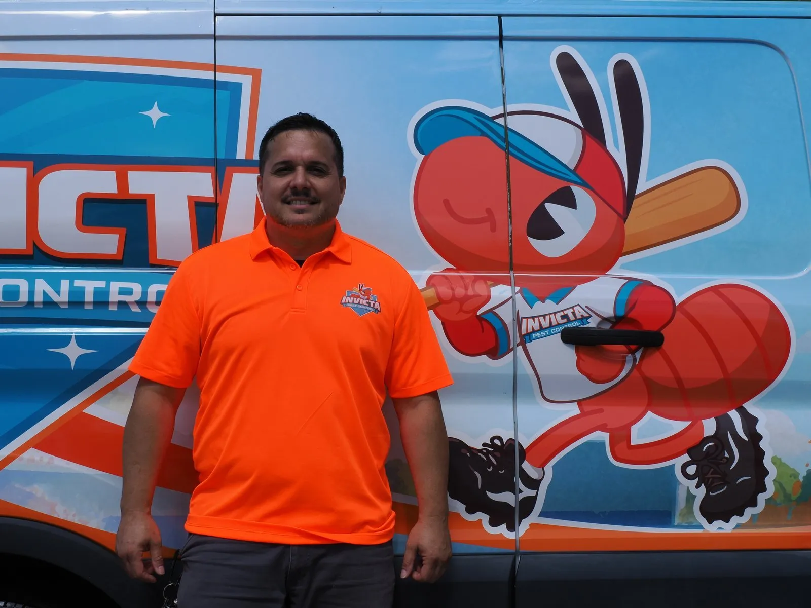 Invicta Pest Control technician in front of the ant mascot on the van