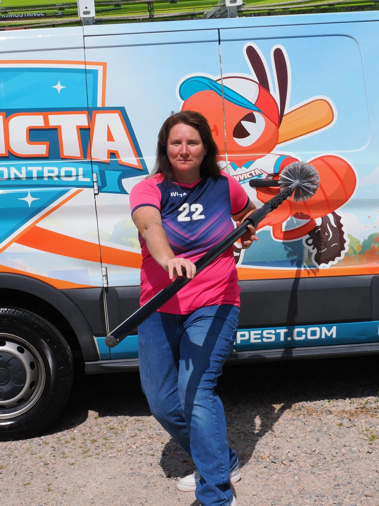 Elizabeth Gilbert with a web brush in front of an Invicta Pest Control van