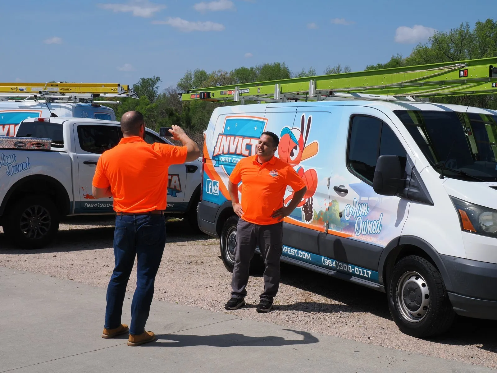 Two Invicta technicians by the vans, one taking the other’s photo