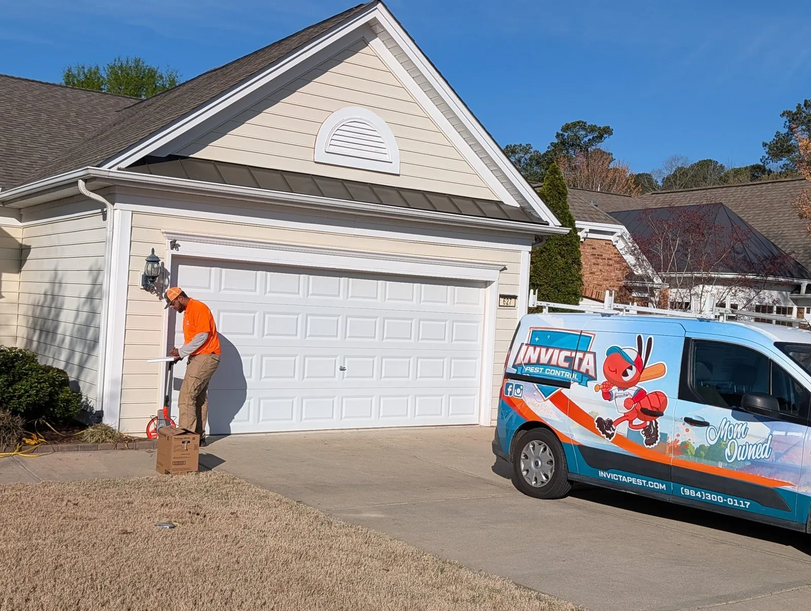 Invicta technician treating around a garage, with the van in the driveway