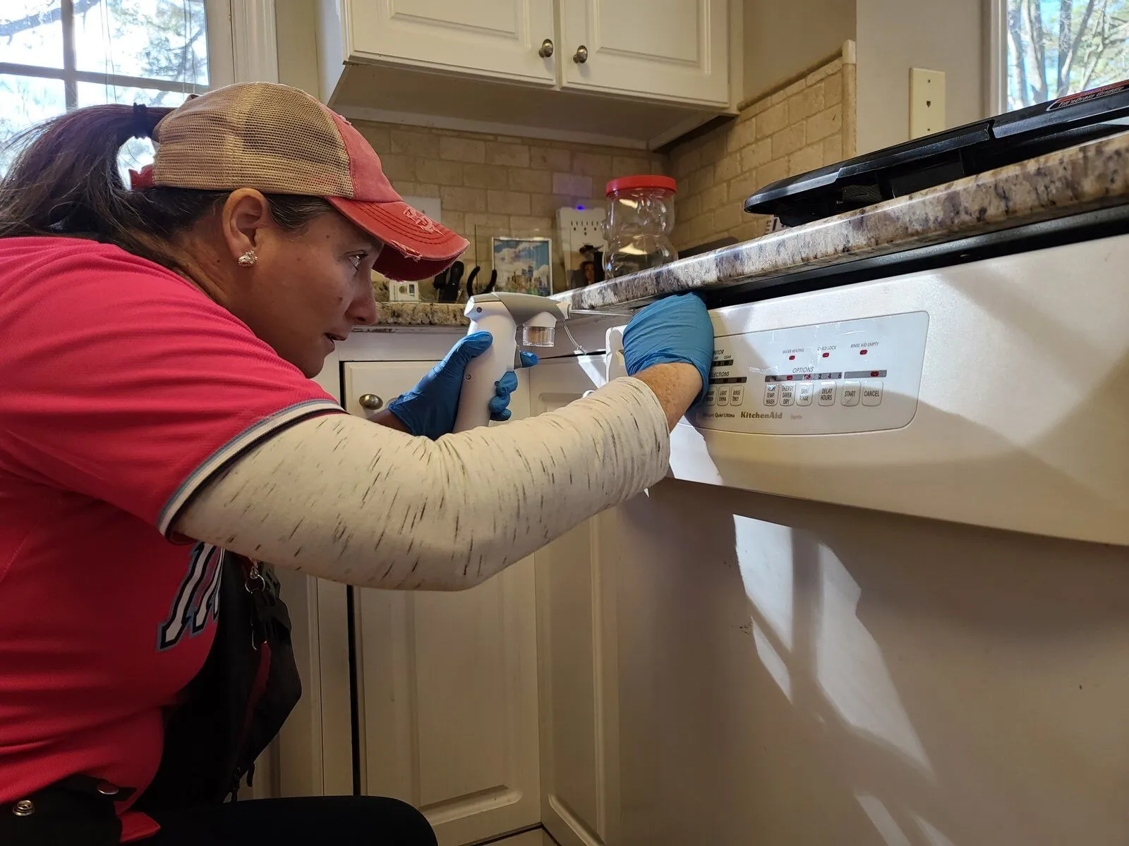 An Invicta technician applying a crack-and-crevice treatment in a kitchen